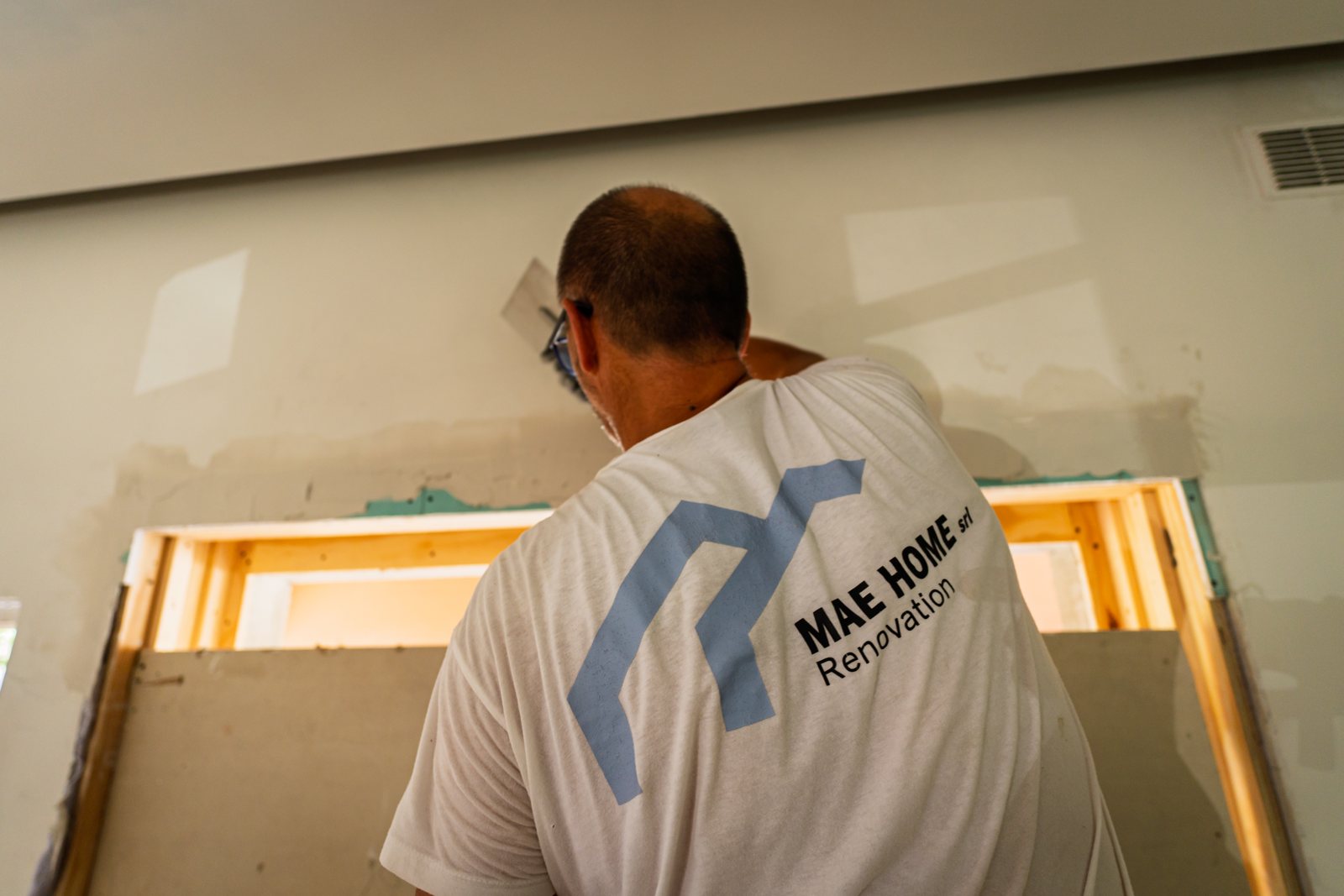 Un operaio con la maglia Mae Home, di spalle, al lavoro su uno dei varchi nuovi visto da dentro
