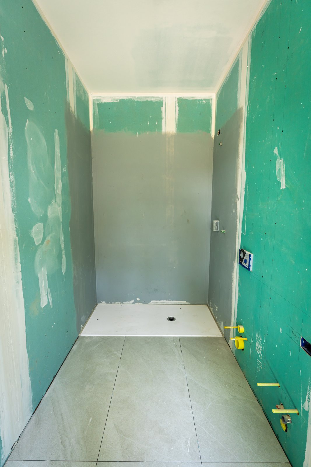 Il bagno con le pareti in cartongesso verde e il piatto doccia, prima del rivestimento