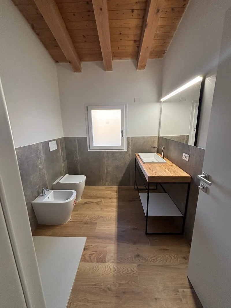 Un bagno rifatto da Mae Home, con le travi in legno a vista e il mobile lavabo sospeso