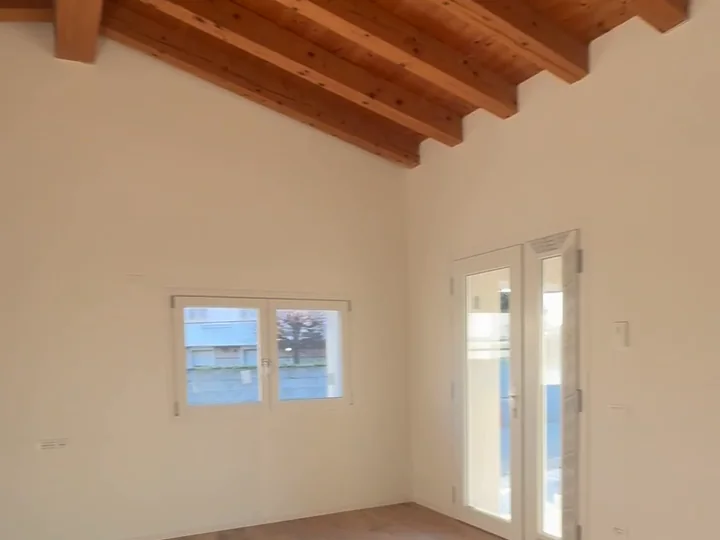 Una casa finita da Mae Home: la camera sotto le travi in legno, con la portafinestra