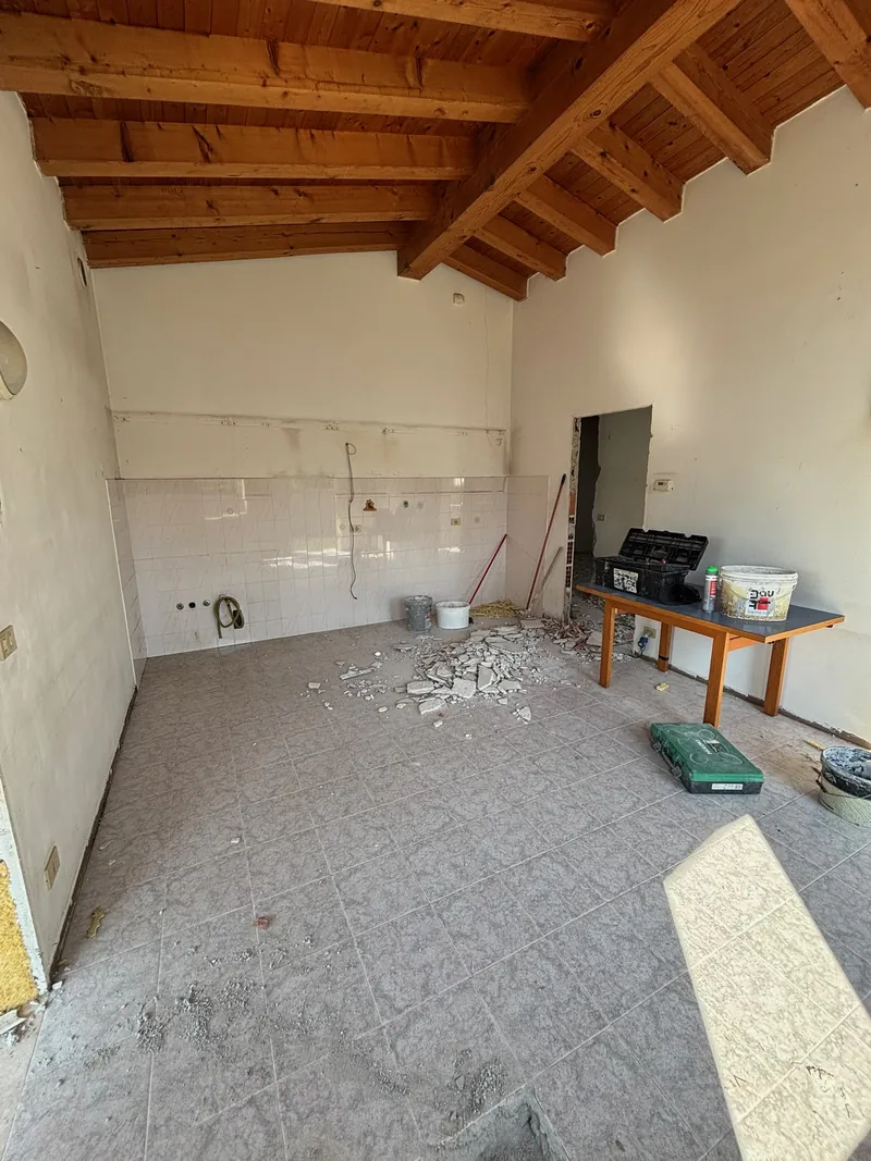 Prima dei lavori: una stanza sotto le travi in legno, con le piastrelle vecchie