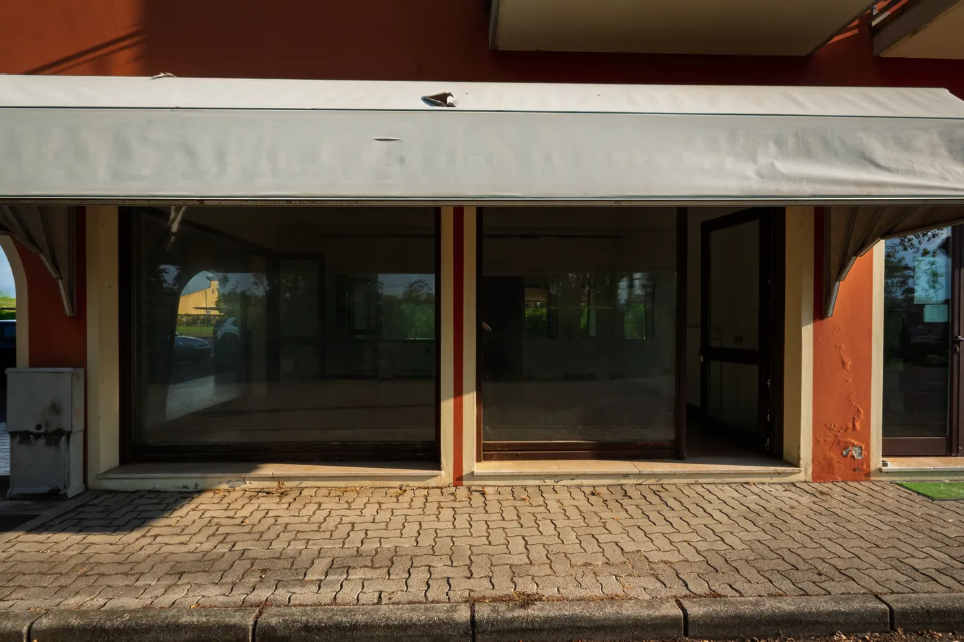 Ottava Presa, prima, a giugno: il negozio da fuori, con le vetrine a nastro e la tenda da sole